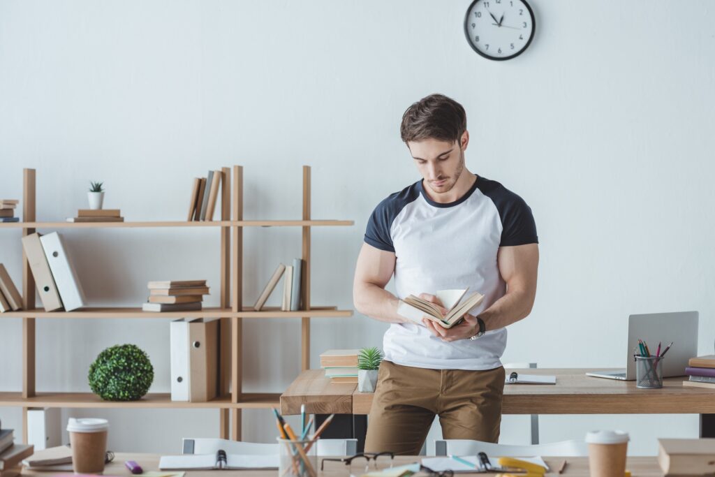male student studying with book in room